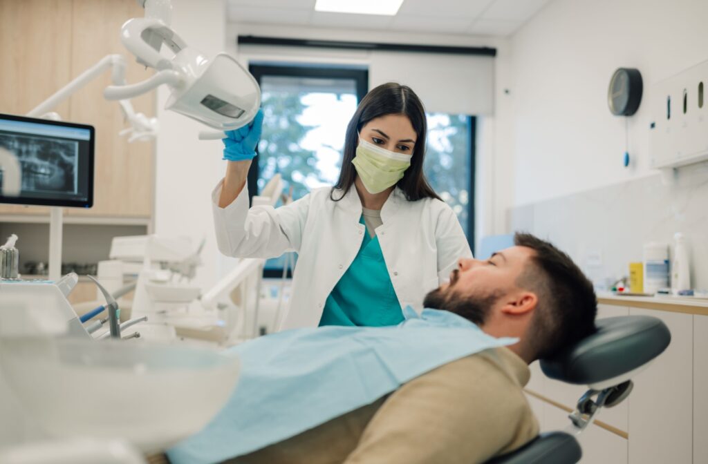 A dentist positioning dental x-ray equipment over patient lying in dentist chair.