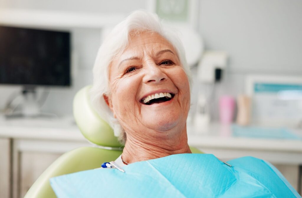 A person smiling in a dental chair during an appointment.